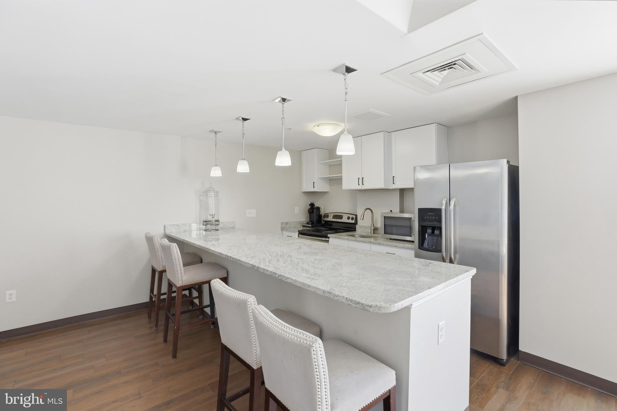 6301 Edsall Road, Unit 106 Alexandria, VA 22312 - Photo 23 of 28 a kitchen with a table chairs refrigerator and microwave