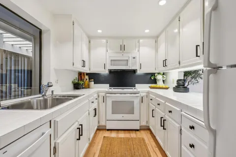 a kitchen with white cabinets and white appliances