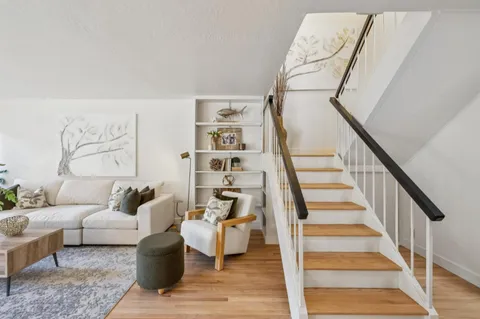 a living room with furniture and stairs with wooden floor