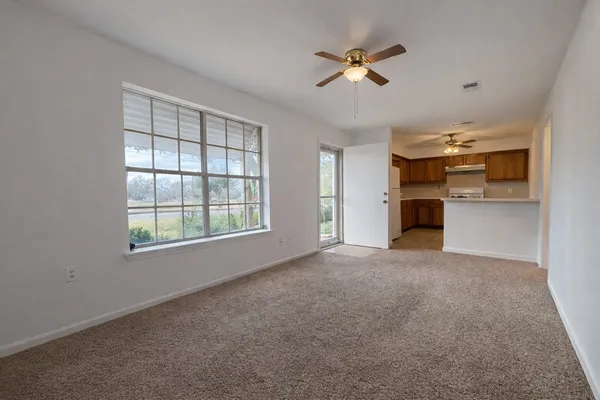an empty room with chandelier fan and windows