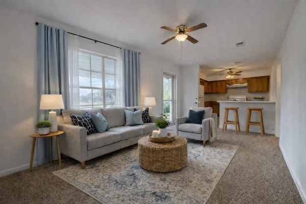 a living room with furniture ceiling fan and a window
