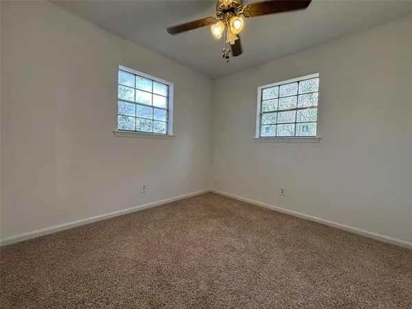 en empty room with windows and chandelier fan