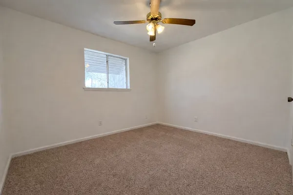 an empty room with a window and a fan