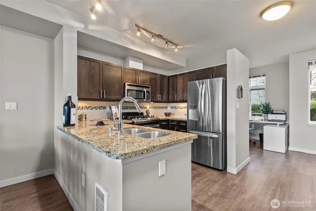 a kitchen with kitchen island granite countertop stainless steel appliances a sink stove refrigerator and cabinets