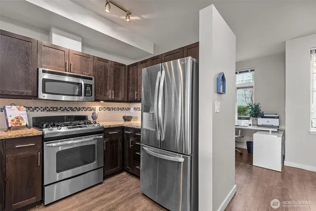 a kitchen with cabinets stainless steel appliances and wooden floor