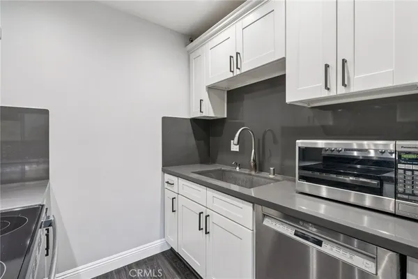 a kitchen with stainless steel appliances granite countertop white cabinets and a stove top oven
