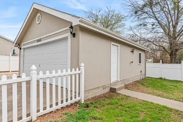 a view of white house with a small yard and wooden fence