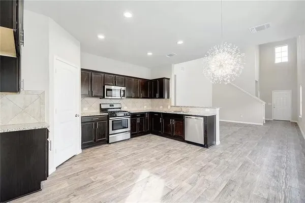 a kitchen with stainless steel appliances granite countertop a stove a sink dishwasher a refrigerator and a oven with wooden floor