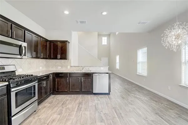 a kitchen with stainless steel appliances granite countertop wooden cabinets stove top oven and sink