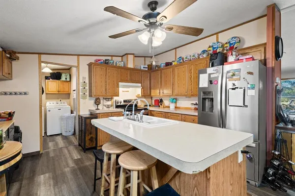 a kitchen with a refrigerator a stove a sink dishwasher and a dining table with wooden floor