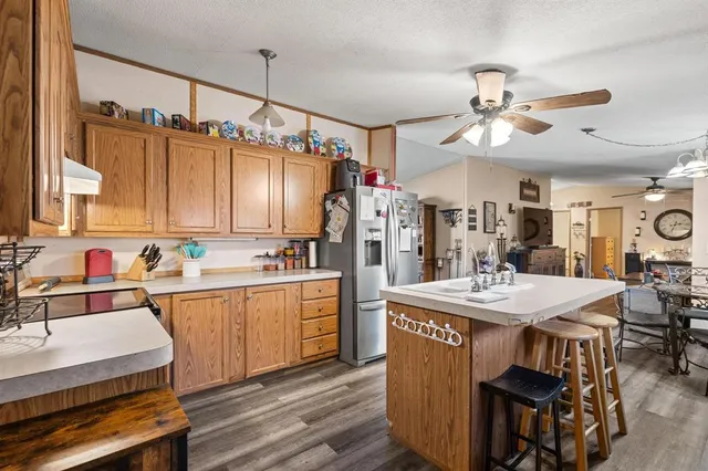 a large kitchen with kitchen island a stove a sink a refrigerator and a dining table