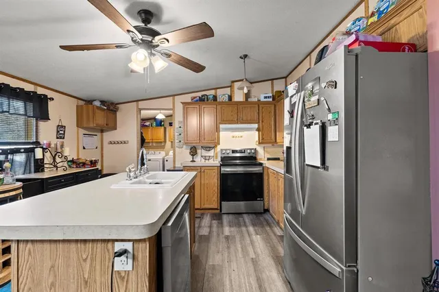 a kitchen with a refrigerator a sink and dishwasher with wooden floor