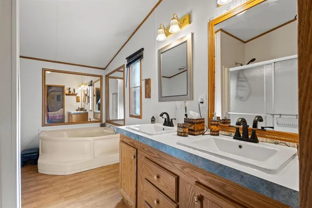 a bathroom with a bathtub a double vanity sink and mirror