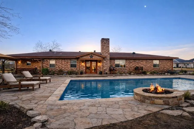 a view of a swimming pool with couches chairs and potted plants