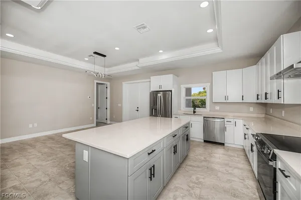 a large white kitchen with a stove a sink a refrigerator and white cabinets with wooden floor