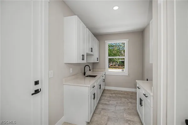 a kitchen with white cabinets and window