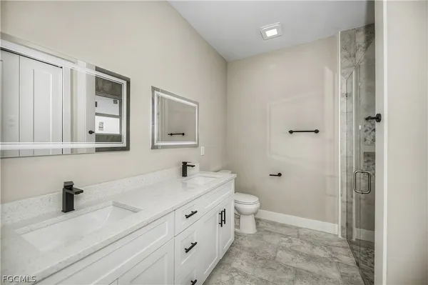 a bathroom with a double vanity sink toilet and mirror