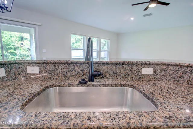 a view of empty room with wooden floor and kitchen