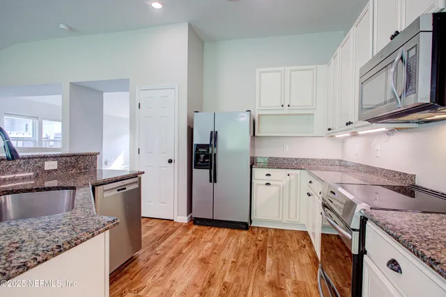 an empty room with wooden floor chandelier fan and windows