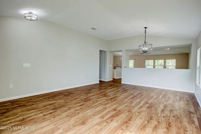 a view of a big room with wooden floor and windows