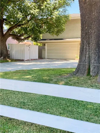 a view of a backyard with large trees and wooden fence