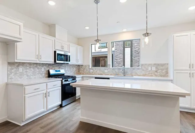 a kitchen with kitchen island granite countertop a sink cabinets and stainless steel appliances