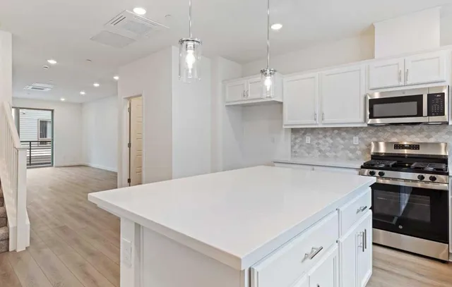 a kitchen with kitchen island a stove a sink a microwave and wooden cabinets