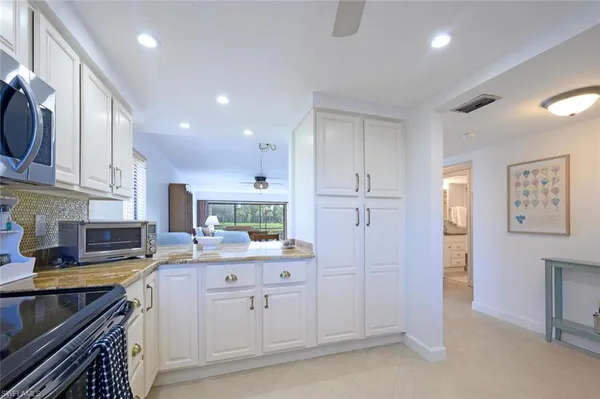 a kitchen with white cabinets and sink
