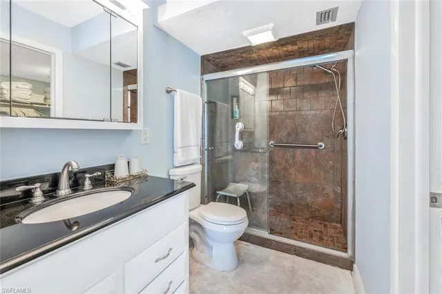 a bathroom with a granite countertop sink a toilet a mirror and shower