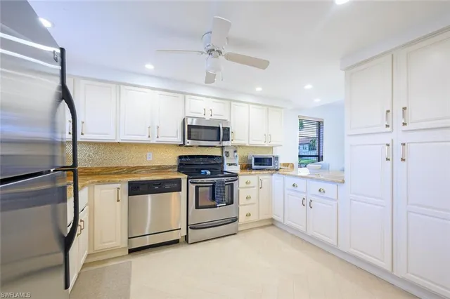a kitchen with granite countertop white cabinets and stainless steel appliances