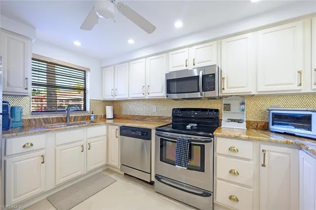 a kitchen with stainless steel appliances granite countertop white cabinets a sink a stove a refrigerator and white cabinets