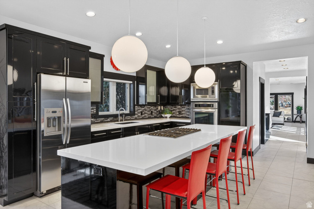 145 Carnesecca Court Mapleton, UT 84664 - Photo 25 of 109 Kitchen with a kitchen bar, stainless steel appliances, a center island, decorative light fixtures, and dark cabinetry