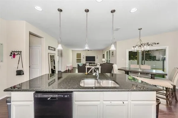 a kitchen with kitchen island granite countertop a sink a counter top space and living room view