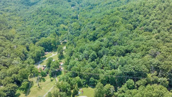 an aerial view of residential house with outdoor space and trees all around