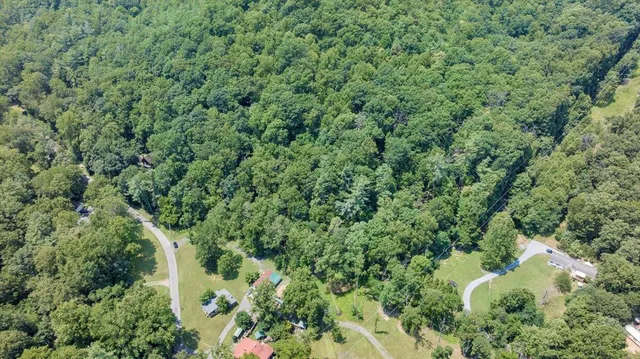 an aerial view of residential house with outdoor space and trees all around