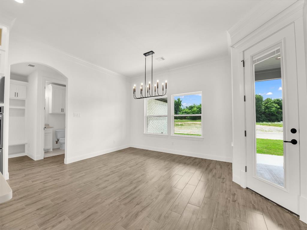 143 Desperado Way Weatherford, TX 76088 - Photo 15 of 36 Unfurnished dining area with light wood-type flooring, crown molding, baseboards, and a chandelier