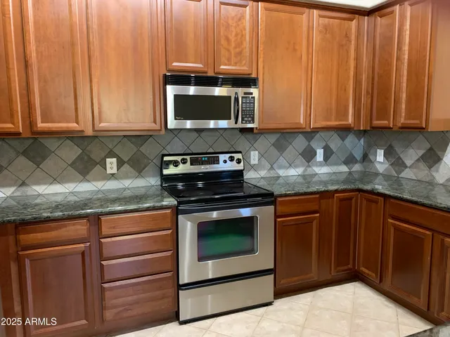 a kitchen with stainless steel appliances granite countertop a refrigerator a sink a stove a microwave and wooden cabinets