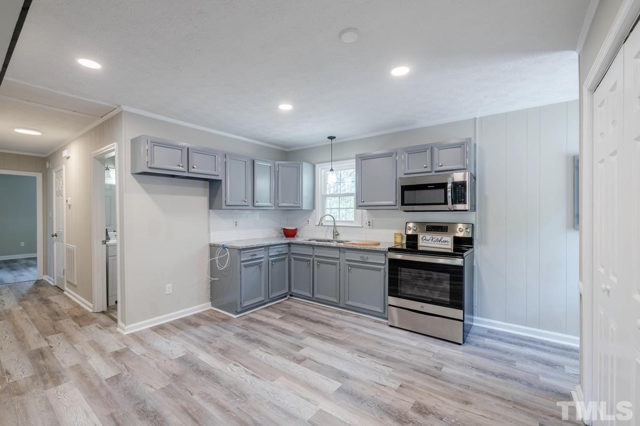 6803 Russell Road Durham, NC 27712 - Photo 6 of 27 a kitchen with stainless steel appliances granite countertop a refrigerator and a stove top oven