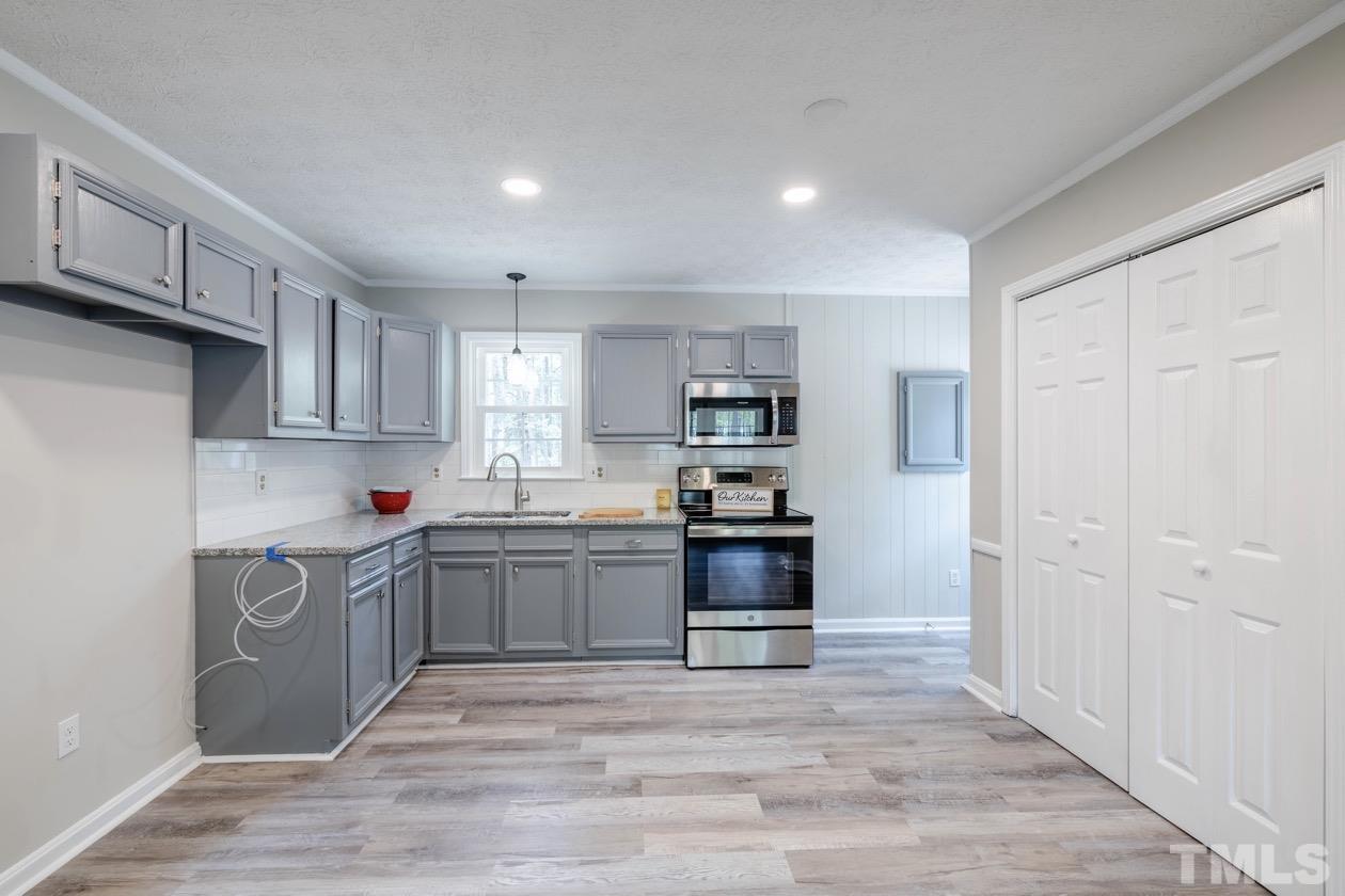 6803 Russell Road Durham, NC 27712 - Photo 7 of 27 a kitchen with stainless steel appliances granite countertop a stove top oven a sink and dishwasher a refrigerator with wooden floors