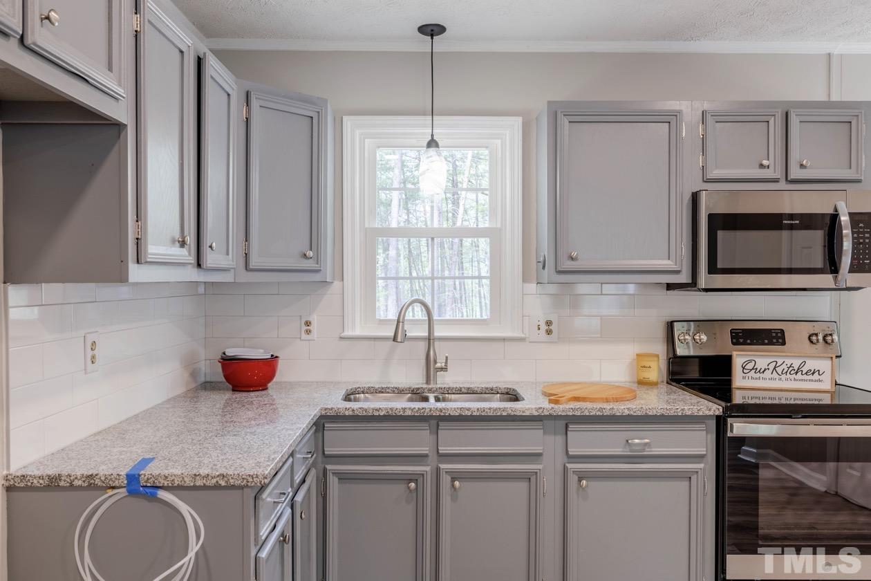 6803 Russell Road Durham, NC 27712 - Photo 8 of 27 a kitchen with stainless steel appliances granite countertop a sink stove and cabinets