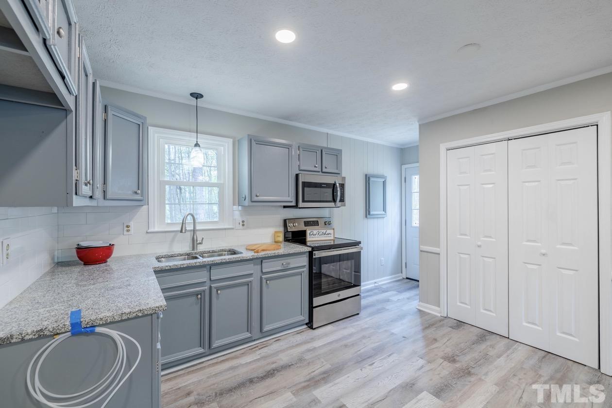 6803 Russell Road Durham, NC 27712 - Photo 9 of 27 a kitchen with granite countertop a sink cabinets stainless steel appliances and a window