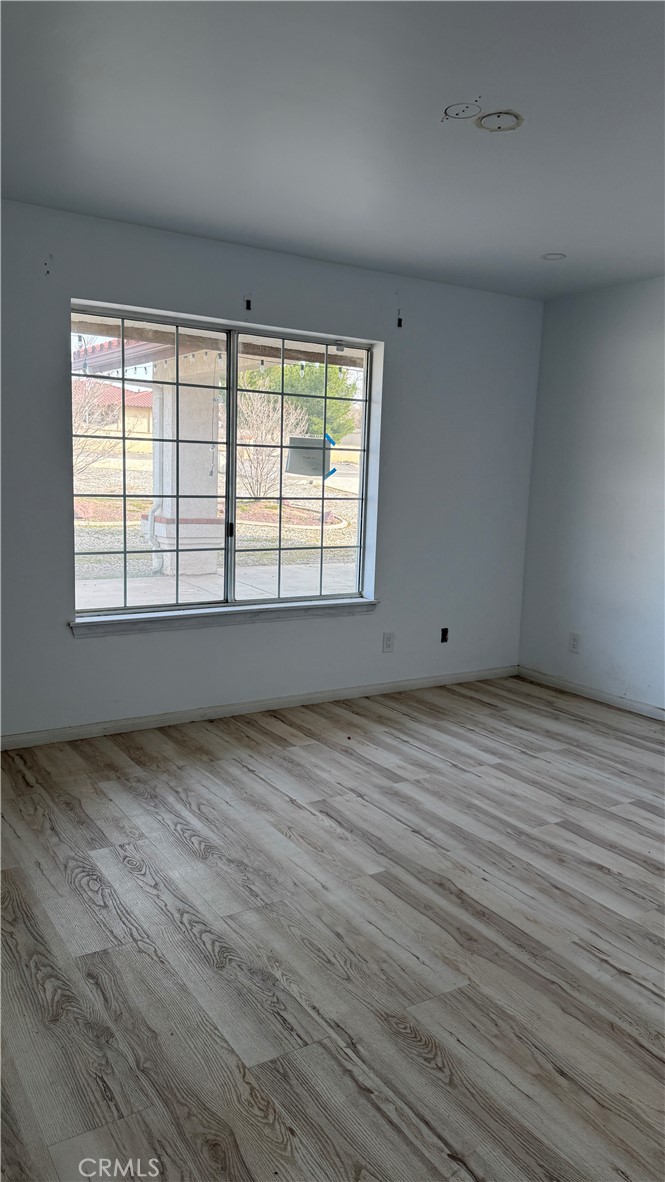 13116 Rincon Road Apple Valley, CA 92308 - Photo 28 of 62 an empty room with wooden floor and windows