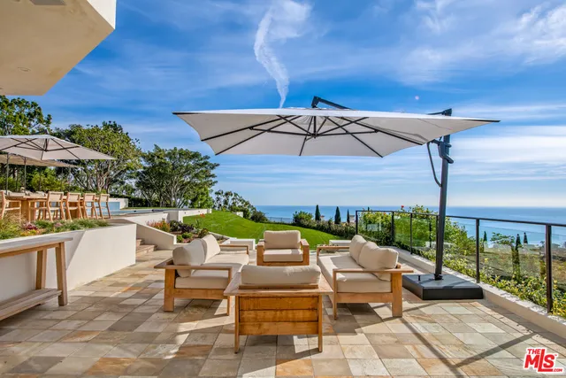 a view of a patio with chairs and a table and chairs under an umbrella