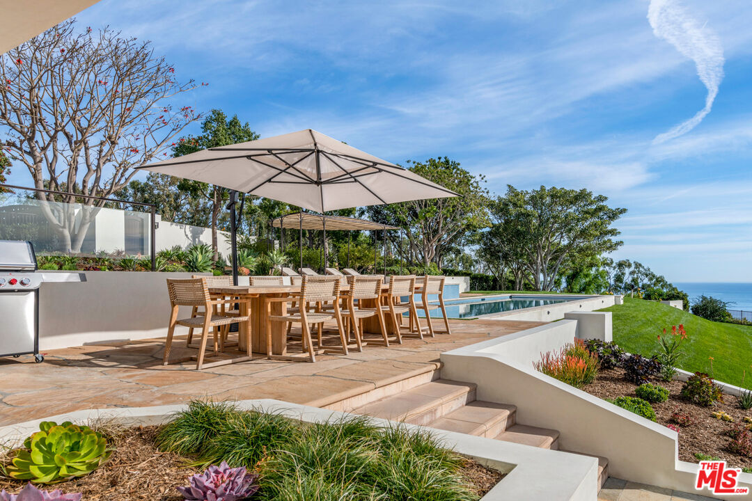 27445 Winding Way Malibu, CA 90265 - Photo 14 of 59 a view of a patio with chairs and a table and chairs under an umbrella
