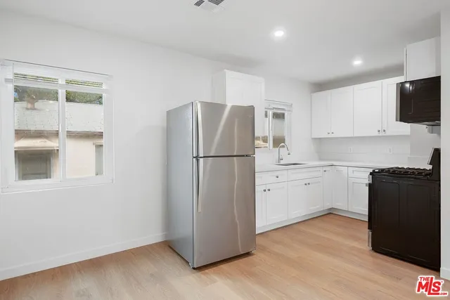 a kitchen with a refrigerator stove and wooden floor