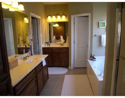 a bathroom with a sink vanity granite tub and a mirror