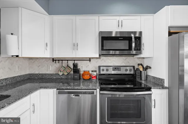 a kitchen with stainless steel appliances granite countertop grey cabinets a stove a sink and dishwasher