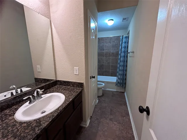a bathroom with a granite countertop sink a toilet a mirror and shower