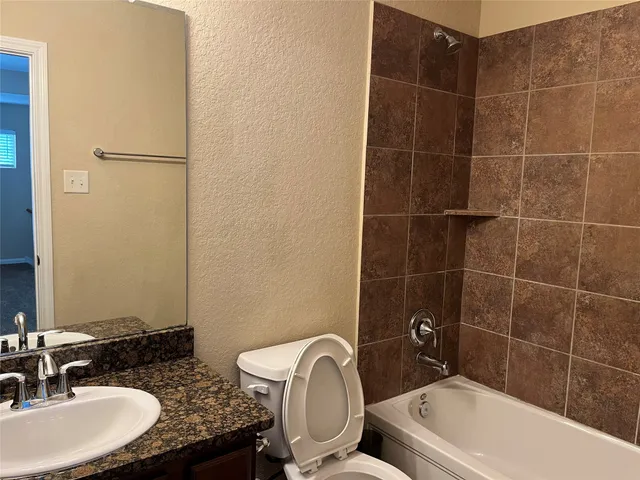 a bathroom with a granite countertop sink a toilet and mirror