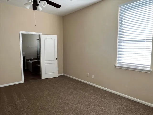 an empty room with chandelier fan and windows